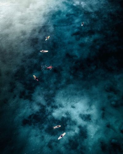 Aerial view of people paddleboarding in sea
