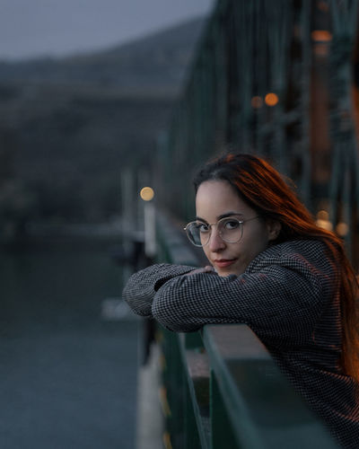 Portrait of woman leaning onto railing of bridge