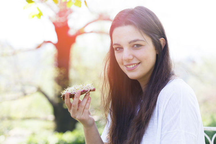 Portrait of smiling young woman holding leaf