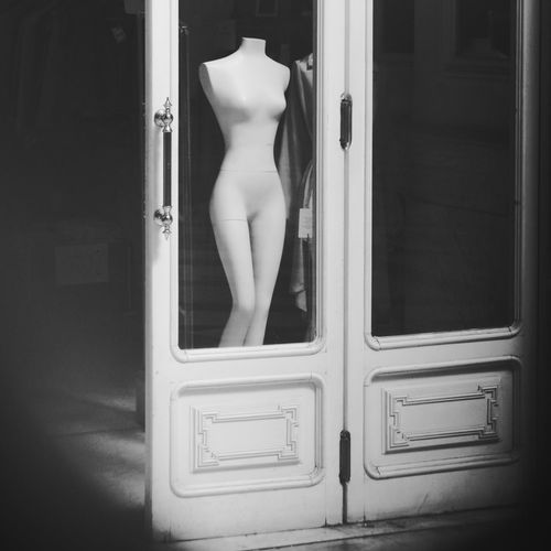 Headless mannequin seen from glass door