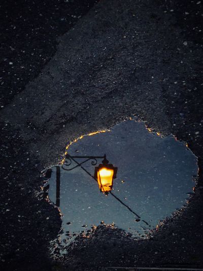 High angle view of puddle with reflection of illuminated street light at night