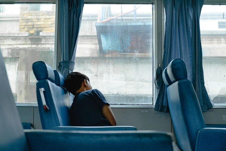 Man looking through window while sitting in train