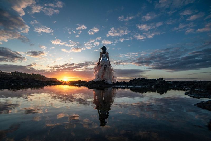 Woman standing in water at sunset