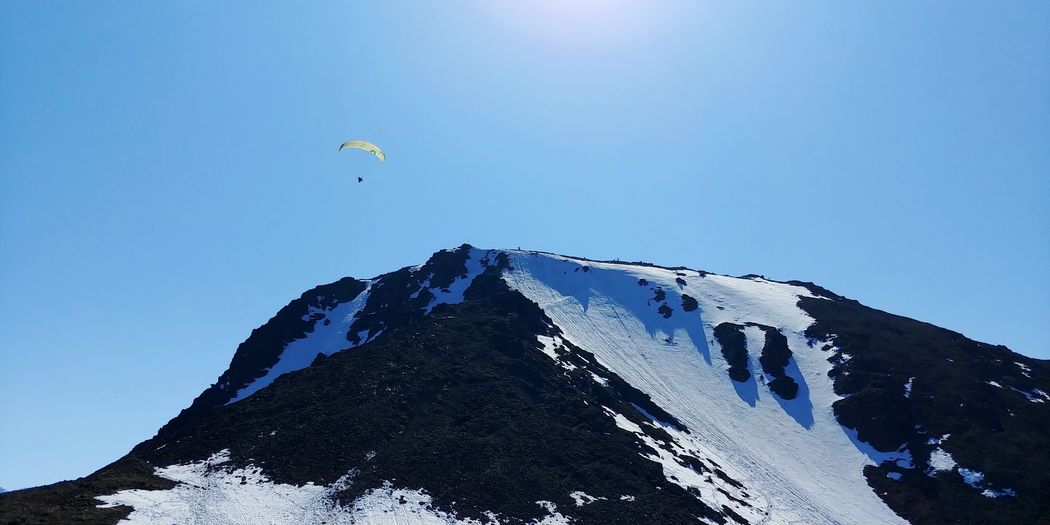 Parasailing snow covered mountain against sky