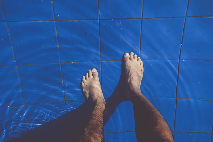 Low section of man standing in swimming pool
