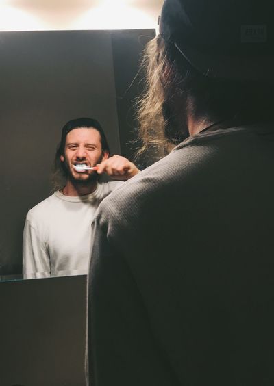 Reflection of man brushing teeth in mirror at home