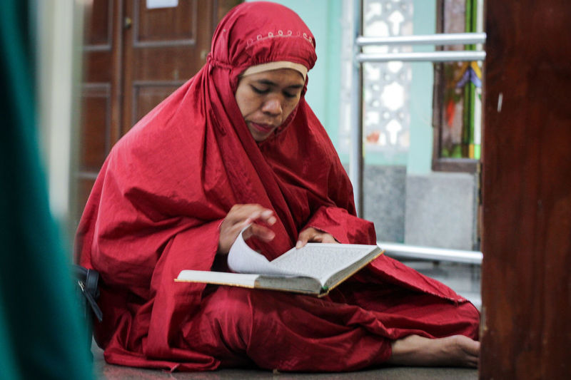 Portrait of young woman in muslim clothes reading the qur'an