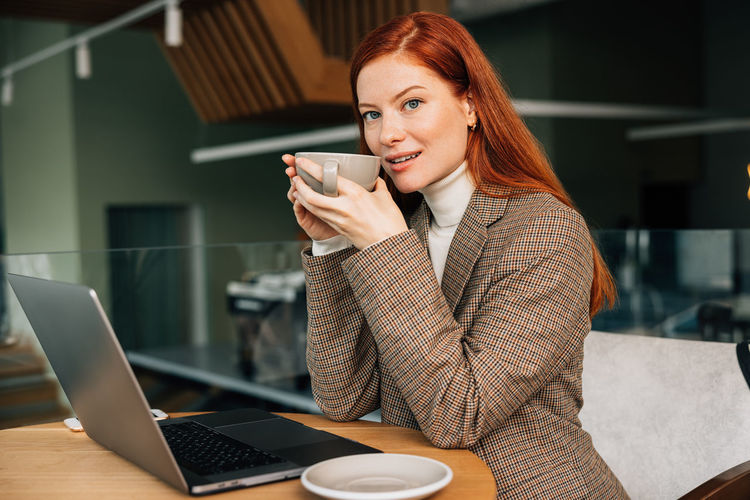Young businesswoman using laptop while sitting on table