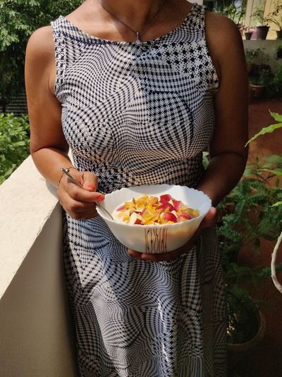 Midsection of woman holding bowl with breakfast cereal