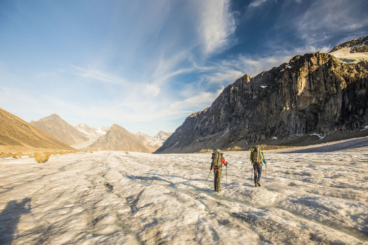 Rear view of backpackers crossing glacier