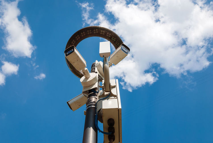 Low angle view of surveillance camera against blue sky