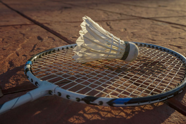 High angle view of badminton racket with shuttlecock on paving stones