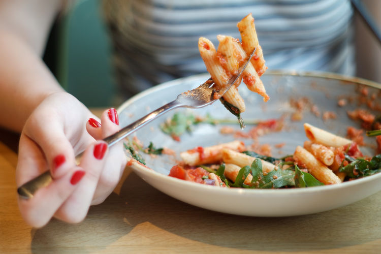 Midsection of woman having pasta at table