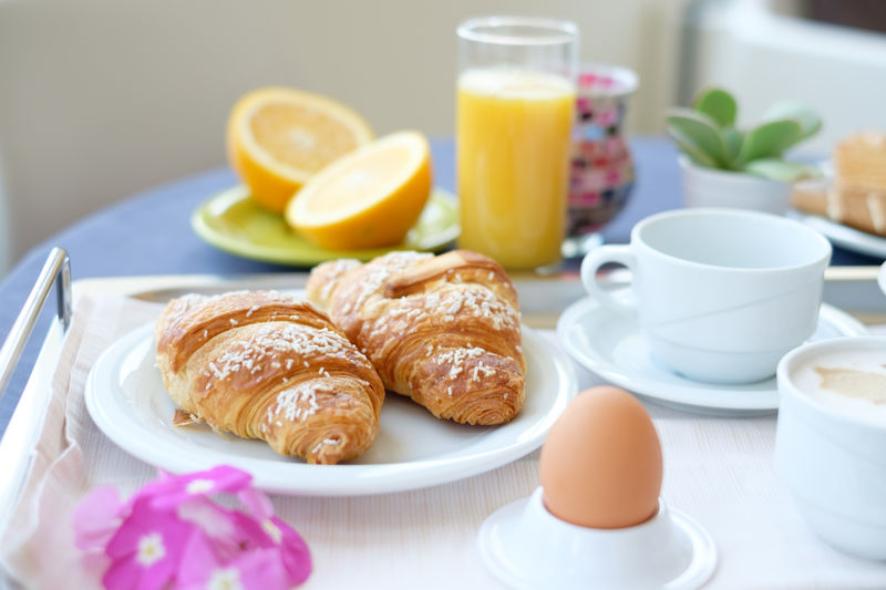 Croissants by egg and orange juice served on table