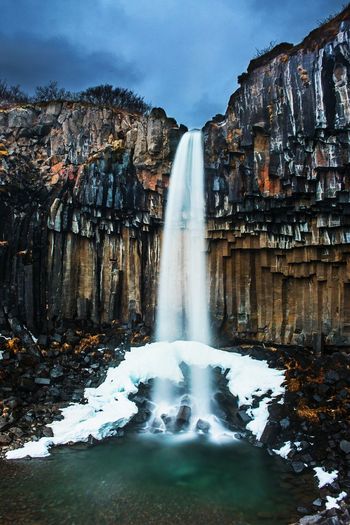 Scenic view of waterfall against sky
