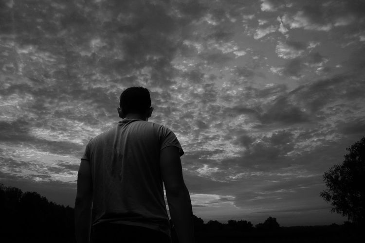 Rear view of silhouette man standing against sky
