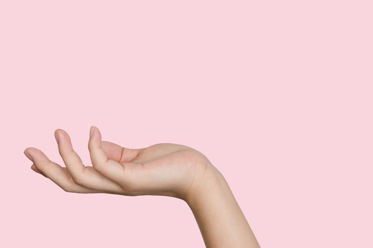 Cropped hand of woman gesturing against pink background
