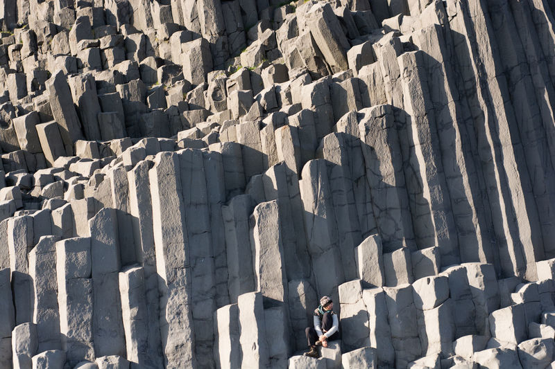 Full length of woman sitting on basalt columns at vik