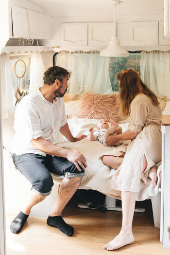 Family with baby on the bed in trailer in the morning. newborn child traveling in camper with