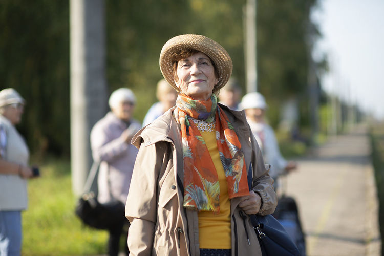Portrait of smiling senior woman wearing summer hat traveling on during covid-19 pandemic