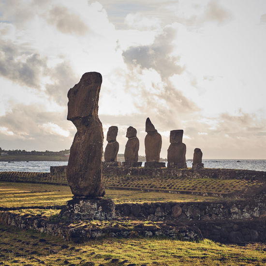 Moai statues on field against sky on easter island