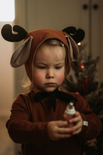 Toddler baby girl in rudolph reindeer costumes decorating christmas tree christmas tree