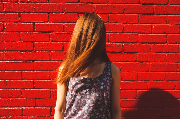 Woman with brown hair against red brick wall