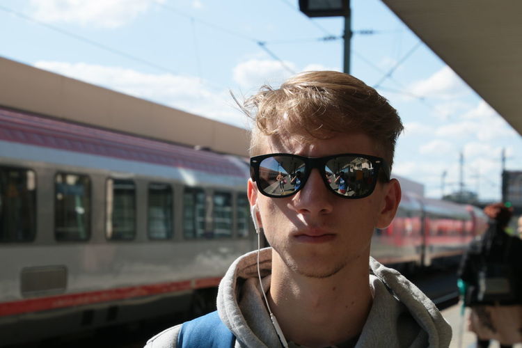 Man listening music while standing at railroad station platform
