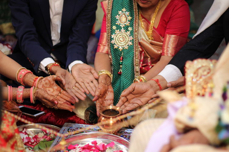 Midsection of family touching container in wedding ceremony