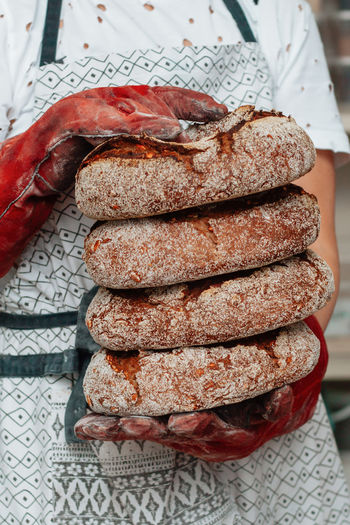 Baker holding in hands a bunch of fresh bread