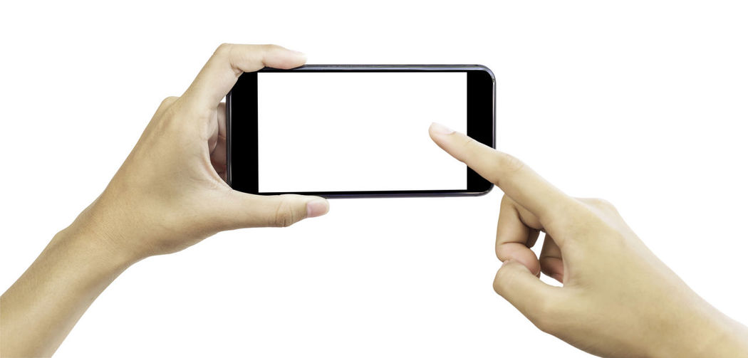 Low section of person holding smart phone against white background