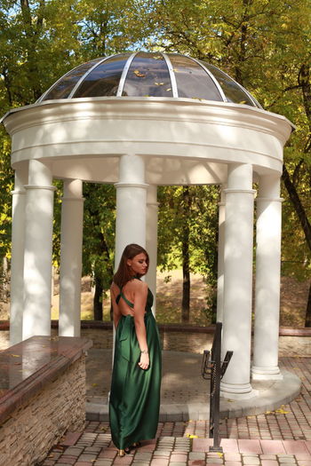 Sexy brunette posing outside in autumn park in a green silk dress