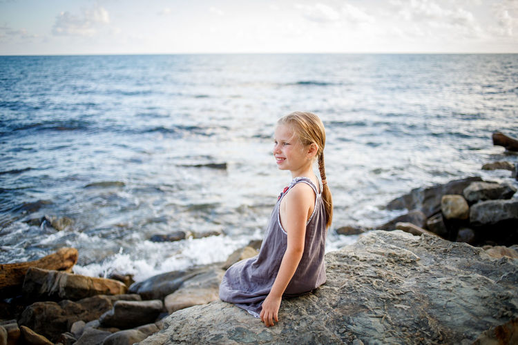 Side view of woman looking at sea against sky