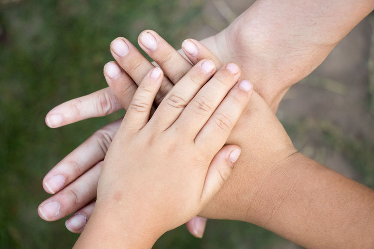 Cropped image of friends stacking hands over field