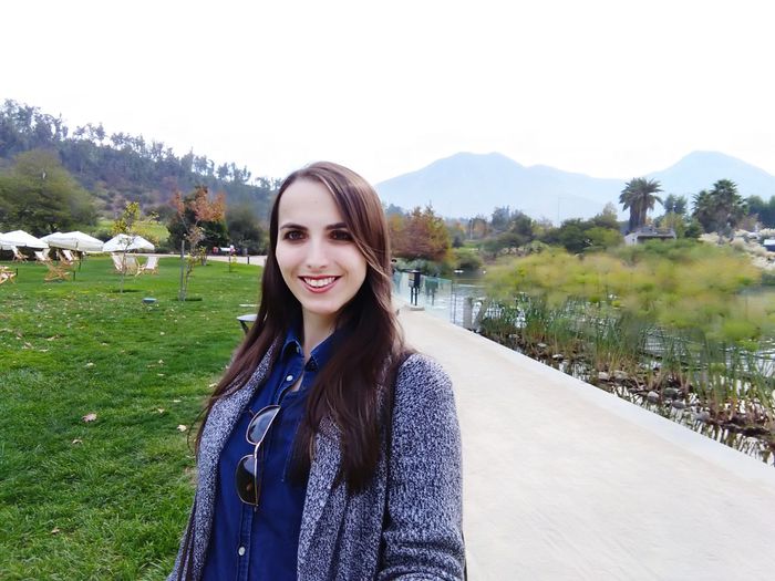 Portrait of smiling young woman standing against sky