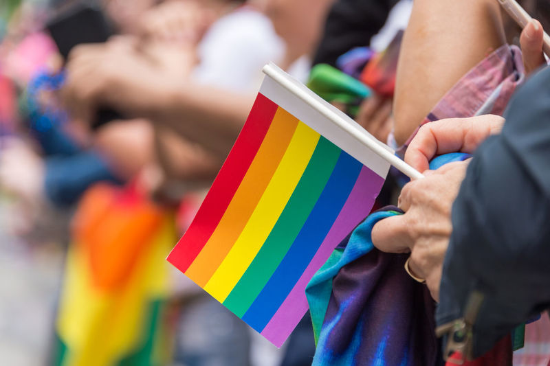Close-up of hand holding rainbow flag
