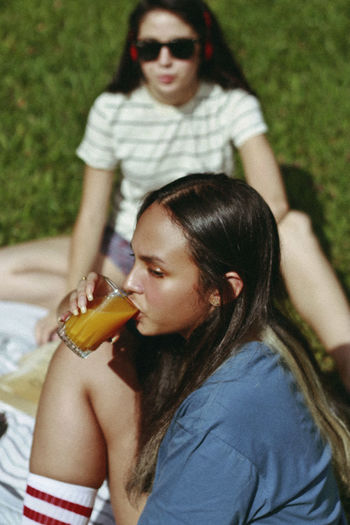 YOUNG WOMAN HOLDING DRINK WITH SUNGLASSES AND OUTDOORS