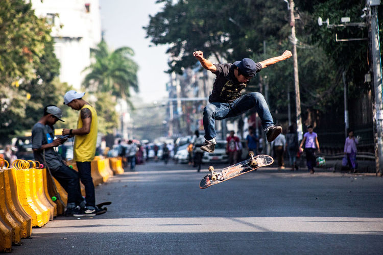 Young man skateboarding on road in city