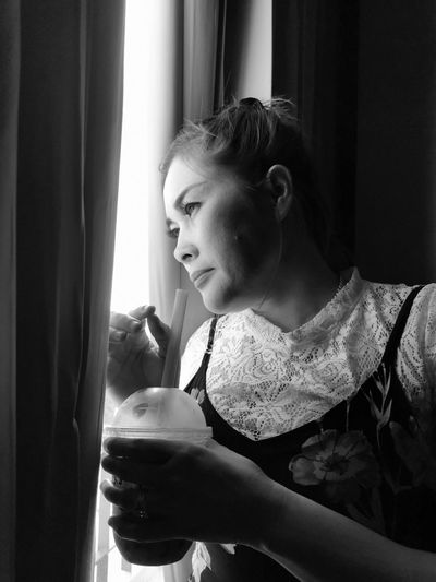 Woman having drink while looking through window