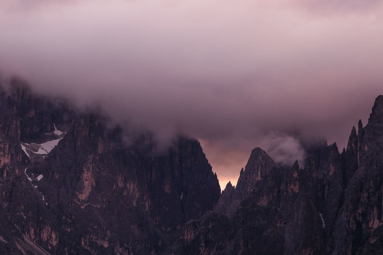 Panoramic view of mountains against sky with storm clouds during sunset