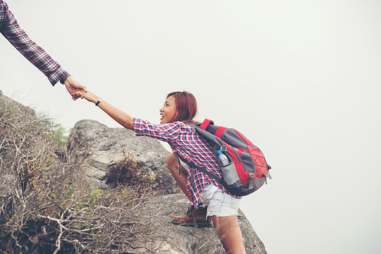 Cropped hand of man assisting female hiker climbing mountain