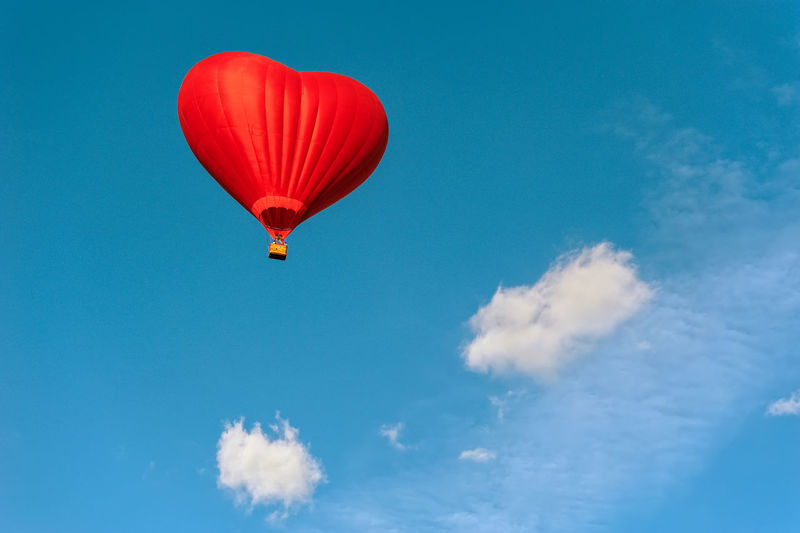 Low angle view of red heart shape hot air balloon against blue sky
