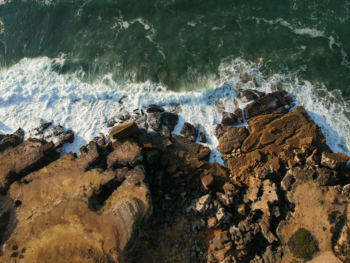 Aerial view of sea waves splashing on rocks