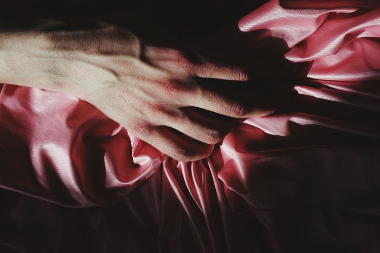 Cropped hand of person on pink textile
