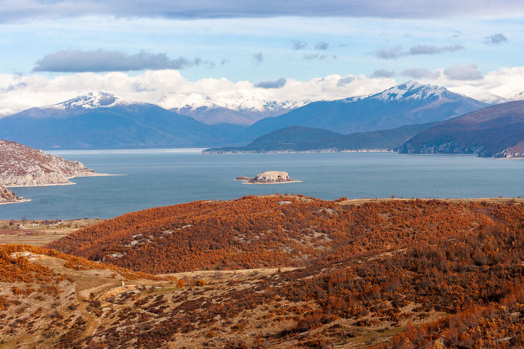 Scenic view of lake by mountains against sky