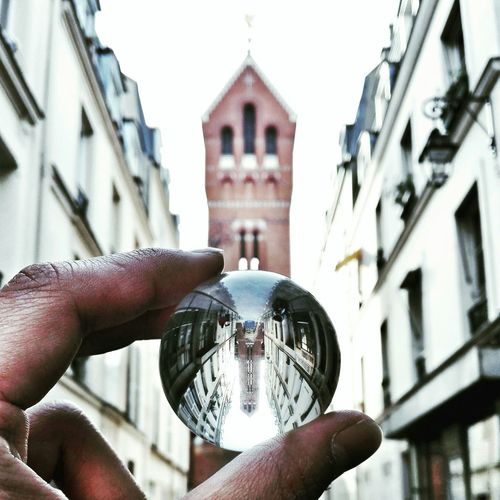 Cropped hand holding crystal ball with reflection of historic building in it