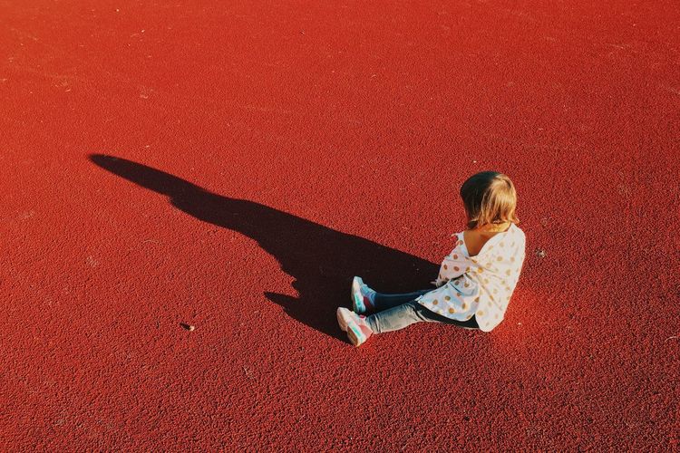 High angle view of girl relaxing on red shadow