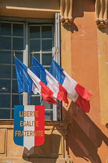View of flags in the wind at the city hall building of vence, in the french provence.