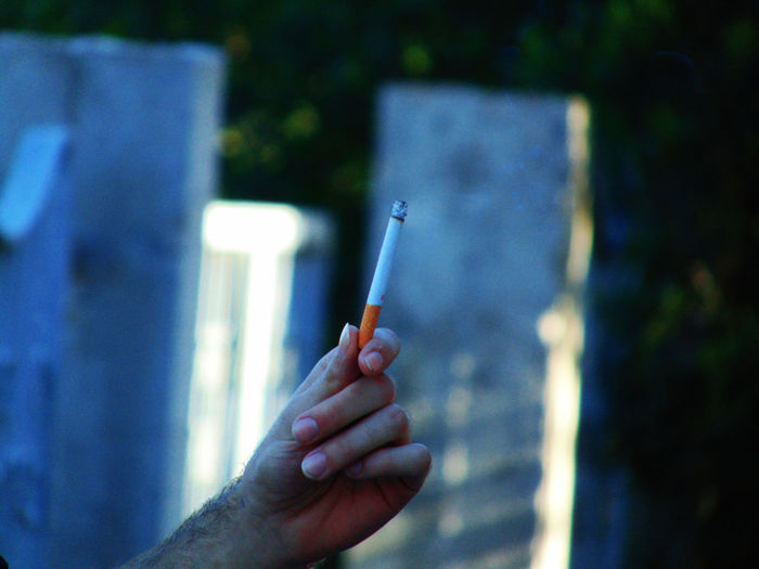 Cropped hand of man holding burning cigarette