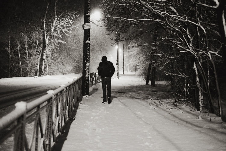 Rear view of man walking on snow covered road